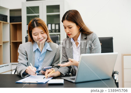 Businesswomen work and discuss their business plans. A Human employee explains and shows her colleague the results paper 138945706