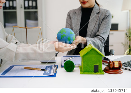 A lawyer presenting a green house model and earth globe with a gavel showing environmental law eco policy sustainability justice and global A lawyer presenting a green house model and earth globe with a gavel showing environmental law eco policy sustainability justice and global 138945714
