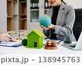 A lawyer presenting a green house model and earth globe with a gavel showing environmental law eco policy sustainability justice and global 138945763
