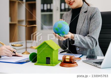 A lawyer presenting a green house model and earth globe with a gavel showing environmental law eco policy sustainability justice and global A lawyer presenting a green house model and earth globe with a gavel showing environmental law eco policy sustainability justice and global 138945763