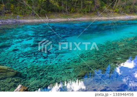 Fantastic view of the Five Colored Pool (the Colorful Pond) with azure crystal clear water among fall woods and evergreen forest in Jiuzhai Valley National Park in China. Fantastic view of the Five Colored Pool (the Colorful Pond) with azure crystal clear water among fall woods and evergreen forest in Jiuzhai Valley National Park in China. 138946456
