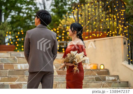 結婚式場のナイトウェディングでカラードレス姿の新郎新婦,ドレスアップした夫婦の後ろ姿 結婚式場のナイトウェディングでカラードレス姿の新郎新婦,ドレスアップした夫婦の後ろ姿 138947237