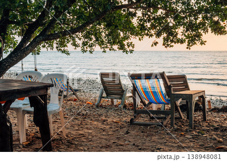 Relaxing beach chairs under tree shade on a quiet tropical beach at late afternoon. 138948081