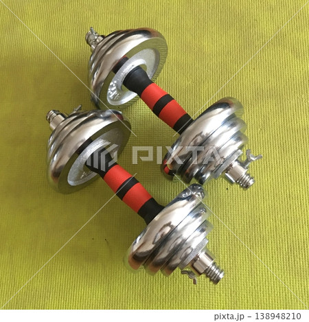 Weights sit on a bright green surface ready for a workout session in a home gym Weights sit on a bright green surface ready for a workout session in a home gym 138948210