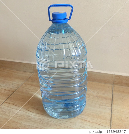 Clear plastic water bottle on a wooden floor in a bright indoor space during the day Clear plastic water bottle on a wooden floor in a bright indoor space during the day 138948247