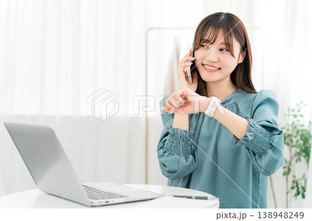 スマホで通話しながらパソコンを使うおしゃれな若いアジア人女性 138948249
