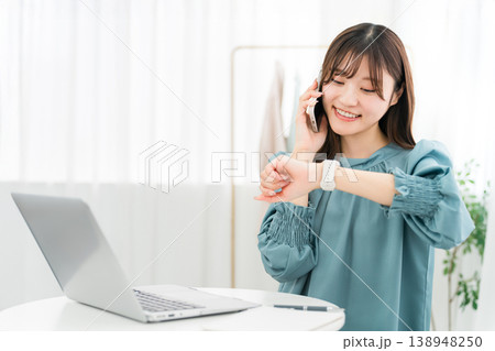 スマホで通話しながらパソコンを使うおしゃれな若いアジア人女性 138948250