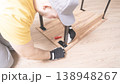 A worker in special clothes collects furniture in close-up. Assembling a new table by the wizard 138948267