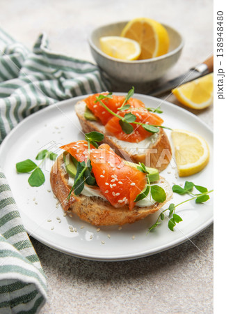 Salmon avocado toasts with microgreens and lemon 138948480