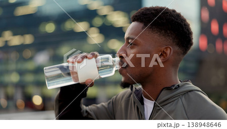 Black man, drinking water and fitness in city after workout, exercise or outdoor training for natural sustainability. Thirsty African male person with mineral drink on break for hydration in town 138948646
