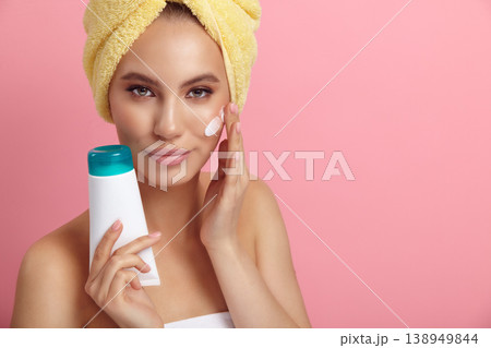 Pretty woman with blank plastic tube applies cream on skin 138949844
