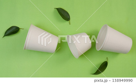 Biodegradable cups on green background with leaves 138949990