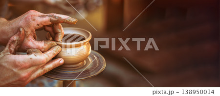 Artisan hands shaping wet clay on a potter's wheel making a pot. Artisan hands shaping wet clay on a potter's wheel making a pot. 138950014