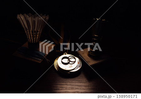 Badminton Pandemic Wedding Concept with Shuttlecock Awards, Mask, and Gold Rings on Wood. 138950171
