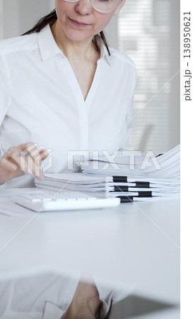 Businesswoman hands organizing stack of papers with binder clips, working on financial documents and official reports in office. Audit and taxes concept 138950621