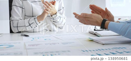 Business people team clapping hands in meeting celebrating success with financial charts, data analysis, sales growth reports, and teamwork achievement in sunny office Business people team clapping hands in meeting celebrating success with financial charts, data analysis, sales growth reports, and teamwork achievement in sunny office 138950681