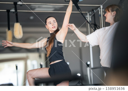 Woman practicing pilates exercise receiving personal instructor guidance 138951636