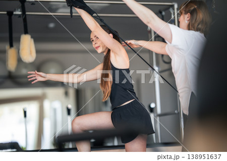 Woman training on pilates reformer with instructor assistance 138951637
