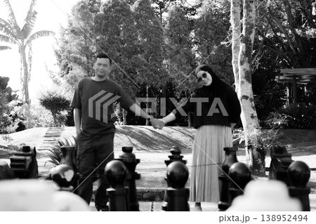 Couple holding hands on giant chess board, black and white concept Couple holding hands on giant chess board, black and white concept 138952494