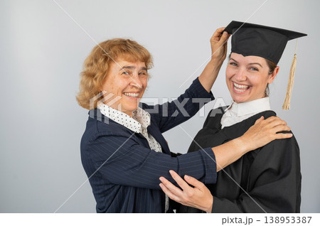 Portrait of Caucasian woman in graduation gown with her mother.  138953387