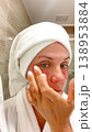 A middle-aged woman applies cosmetic patches to the skin under the eyes.  138953884