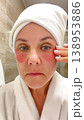 A middle-aged woman applies cosmetic patches to the skin under the eyes.  138953886