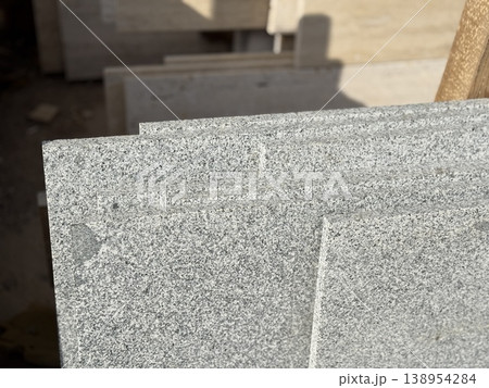 Granite slabs with speckled pattern stacked in sunlight, ideal for construction background Granite slabs with speckled pattern stacked in sunlight, ideal for construction background 138954284