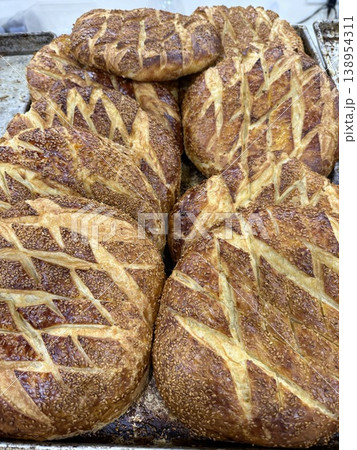 Traditional freshly baked sesame bread loaves with textured crust on a baking tray background Traditional freshly baked sesame bread loaves with textured crust on a baking tray background 138954311