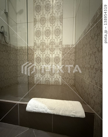 Corner of modern bathroom with elegant tile design and towel on wooden bench Corner of modern bathroom with elegant tile design and towel on wooden bench 138954319