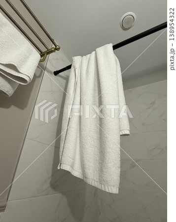 White towel hanging on black rod in modern bathroom setting, suitable for background use 138954322