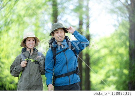 新緑の春の森の中を歩く夫婦のアウトドア、登山やトレッキングなどの運動イメージ上半身の笑顔 138955315