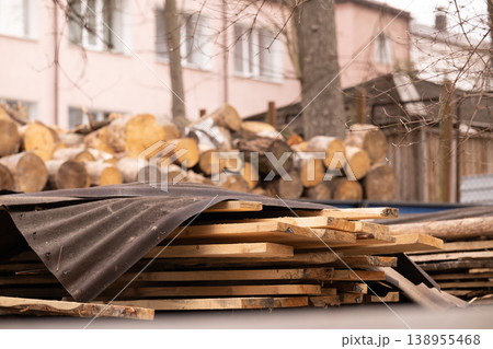 Stack of Raw Timber Planks and Round Wood Logs in Backyard Near House with Soft Daylight Stack of Raw Timber Planks and Round Wood Logs in Backyard Near House with Soft Daylight 138955468