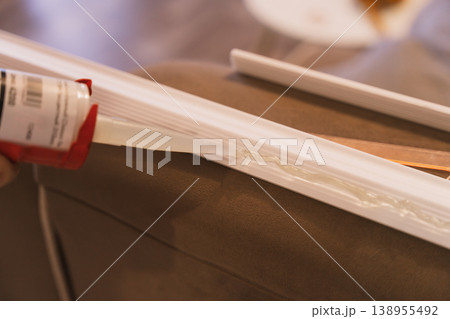 Close up applying construction adhesive to molding strip, DIY home improvement concept 138955492
