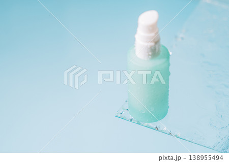 Minimal pump bottle on blue background with glass and water drops Minimal pump bottle on blue background with glass and water drops 138955494