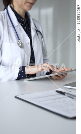 Female doctor using digital tablet during medical consultation in modern clinic. Medicine, healthcare and science concept 138955567