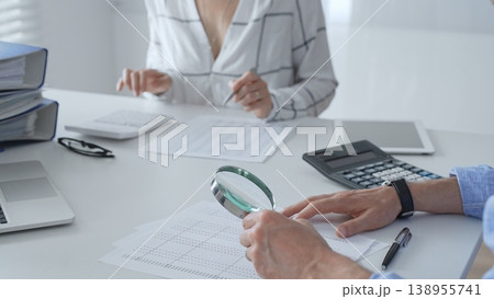 Accounting professionals analyzing financial documents, checking spreadsheet details with calculator and magnifying glass. Audit and taxes in business 138955741