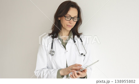 Headshot of a female physician reviewing patient records on digital tablet, standing in contemporary medical workspace with natural lighting. Medicine and health care concept Headshot of a female physician reviewing patient records on digital tablet, standing in contemporary medical workspace with natural lighting. Medicine and health care concept 138955802