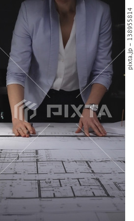 Architect drawing on construction plans, developing a new building design with a ruler and pen on paper. Architecture and business concept in low key lighting Architect drawing on construction plans, developing a new building design with a ruler and pen on paper. Architecture and business concept in low key lighting 138955814