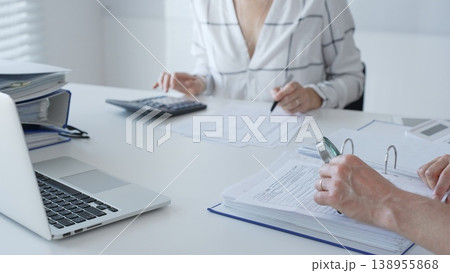 Team of professional accountants working together, using a magnifying glass and a calculators, to audit financial reports in their brightly lit office. Audit and taxes in business Team of professional accountants working together, using a magnifying glass and a calculators, to audit financial reports in their brightly lit office. Audit and taxes in business 138955868