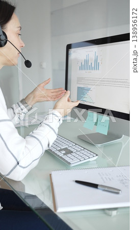 Female call center agent wearing a headset, assisting customers remotely and participating in a virtual office meeting. Professional customer support and business services Female call center agent wearing a headset, assisting customers remotely and participating in a virtual office meeting. Professional customer support and business services 138956172