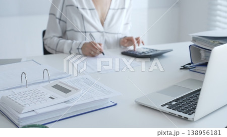 Calculator on financial documents, with an accountant taking notes, emphasizing accounting, finance, and tax preparation, close up. Audit and taxes in business 138956181