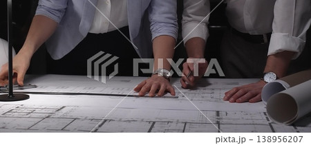 Architects and engineers collaborating on building blueprints using drawing tools at night, planning new projects. 138956207