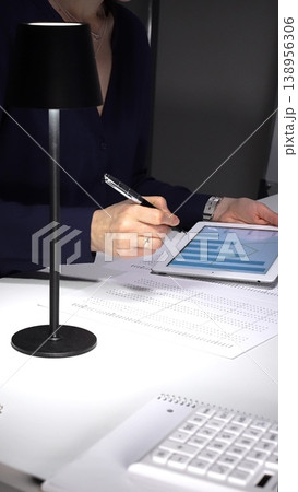 Woman using a tablet with charts and graphs, working late to analyze data and economic statistics for business growth. Audit and taxes theme in business Woman using a tablet with charts and graphs, working late to analyze data and economic statistics for business growth. Audit and taxes theme in business 138956306