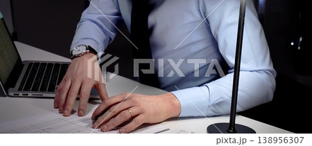 Professional businessman typing on laptop, working late in an office, demonstrating dedication and diligence. Audit and taxes in business 138956307
