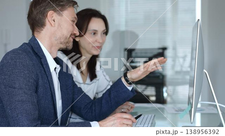 Business colleagues collaborating on computer, discussing project ideas and sharing insights in a modern office. Businesspeople concept 138956392