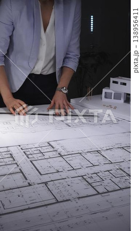 Female architect drawing blueprints for a residential building project, creating innovative urban design plans. Architecture and business concept in low key lighting Female architect drawing blueprints for a residential building project, creating innovative urban design plans. Architecture and business concept in low key lighting 138956411