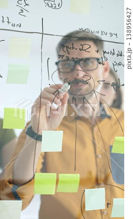 Business people colleagues planning strategy, writing notes on glass wall, collaborating with enthusiasm in bright contemporary office workspace Business people colleagues planning strategy, writing notes on glass wall, collaborating with enthusiasm in bright contemporary office workspace 138956427