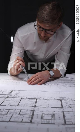 Architect creating technical drawing with compass, designing blueprint on paper for engineering project in office. Concept of architecture and business in low key lighting Architect creating technical drawing with compass, designing blueprint on paper for engineering project in office. Concept of architecture and business in low key lighting 138956507