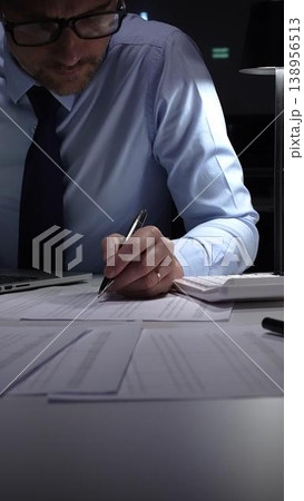 Businessman working meticulously with financial documents, using a pen and calculator to manage accounting tasks and reporting. Audit and taxes in business Businessman working meticulously with financial documents, using a pen and calculator to manage accounting tasks and reporting. Audit and taxes in business 138956513