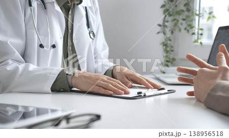 Doctor is explaining diagnosis to patient during a medical consultation in a medical office, gesturing with hands. Medicine and health care concept 138956518